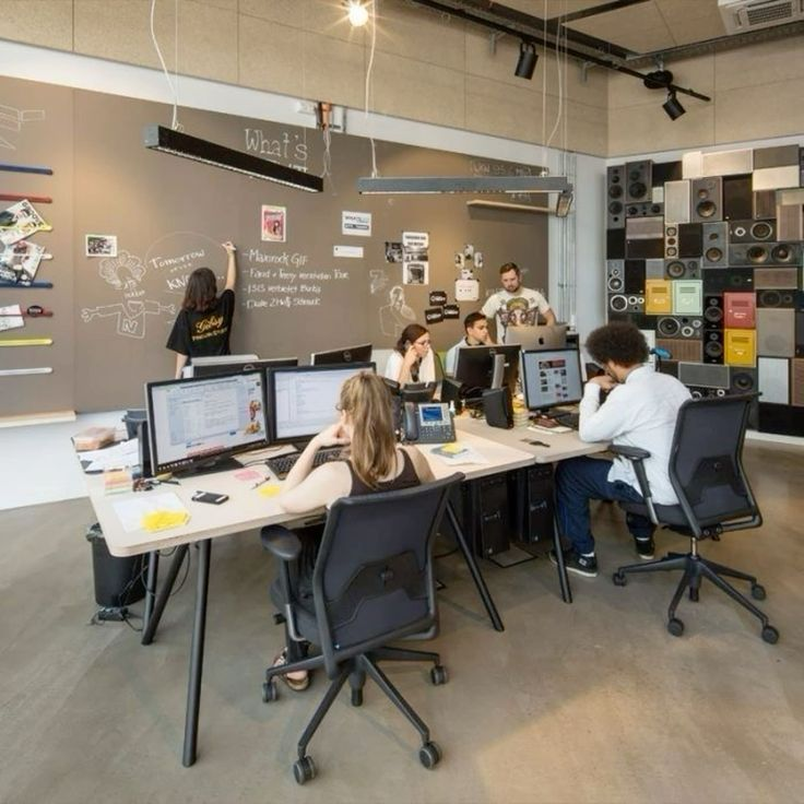 People collaborating in a studio with a wall of ideas